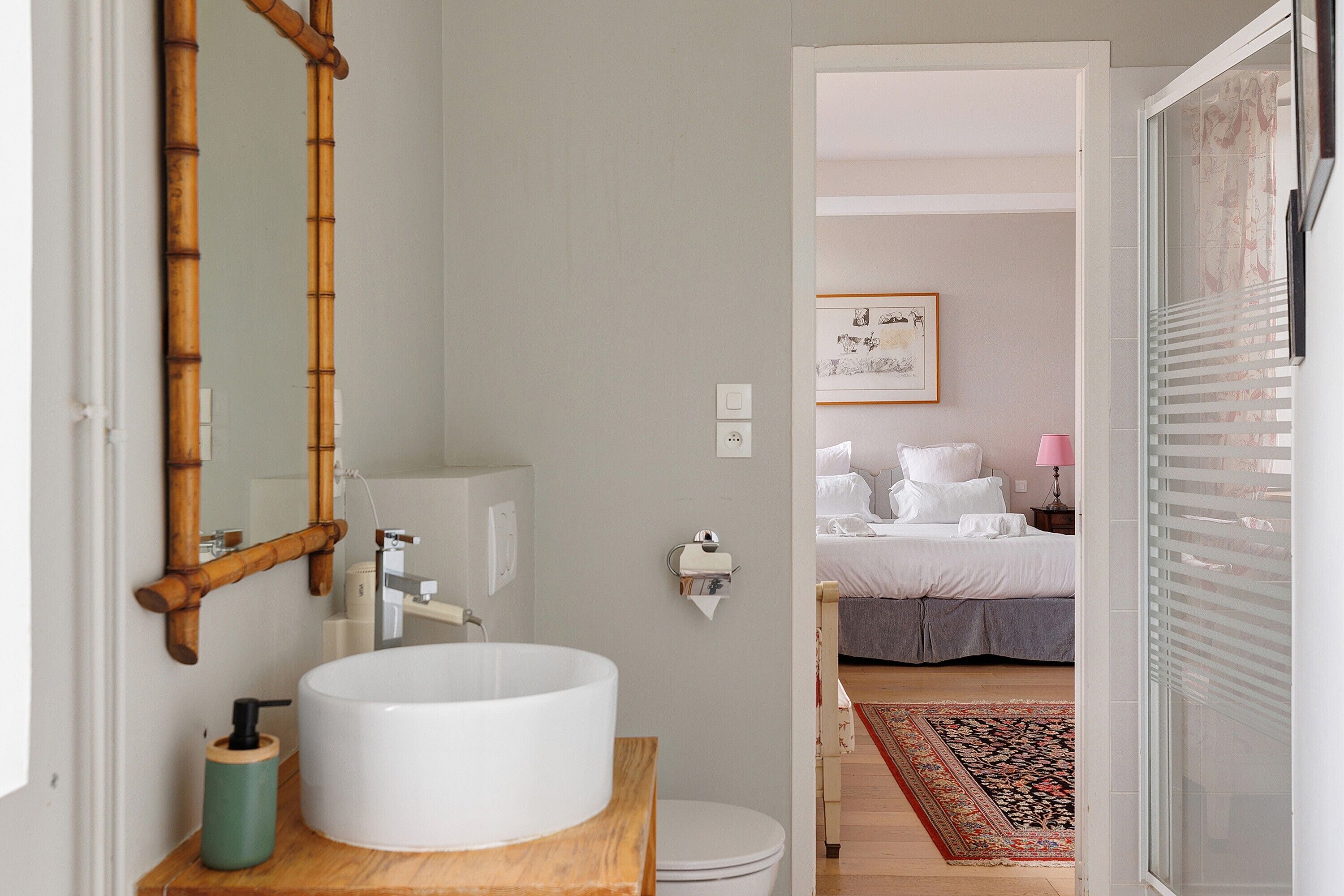 A bathroom with a white sink, bamboo mirror, and a wooden countertop.