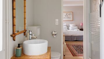 A bathroom with a white sink, bamboo mirror, and a wooden countertop.