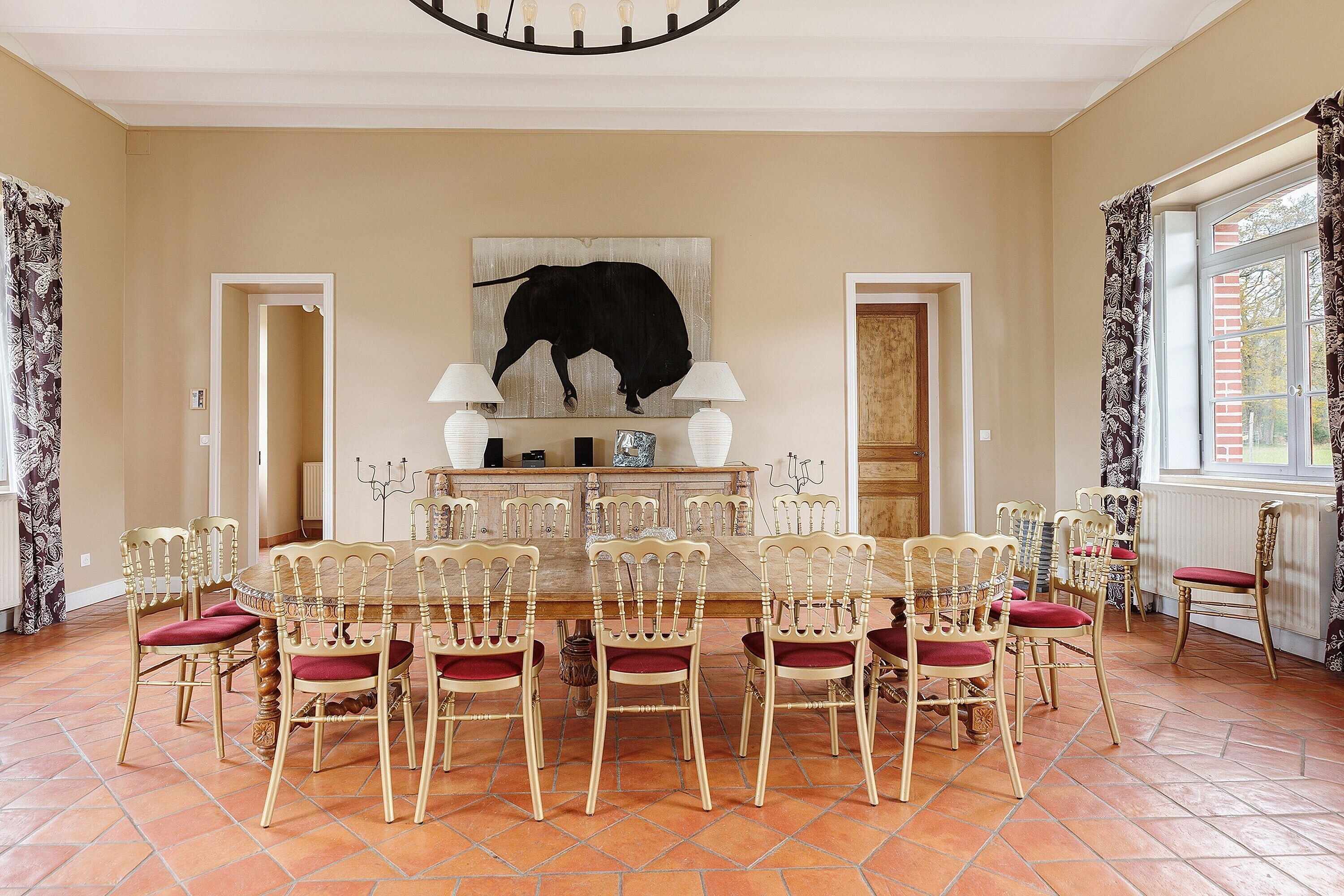 Un coin repas avec une table ronde, des chaises et une œuvre d’art représentant un taureau, accrochée au mur.
