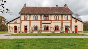 Ein großes, zweistöckiges Gebäude mit einer symmetrischen Fassade, zahlreichen Fenstern und roten Türen.