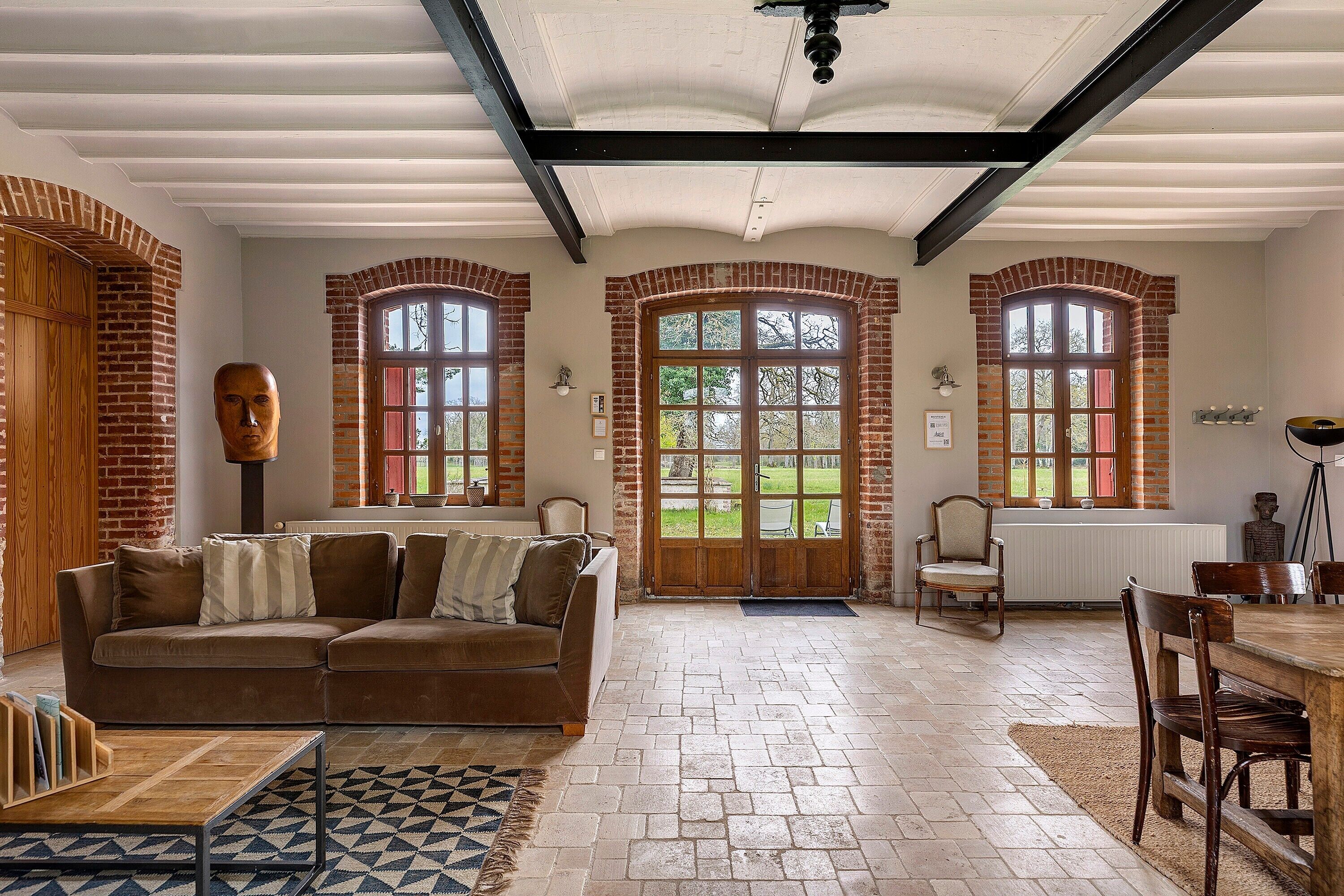 A spacious living area with a brown sofa, a wooden coffee table, and a patterned rug.