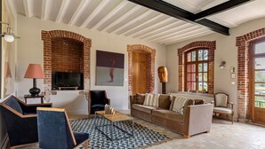 Un salon avec un canapé, des fauteuils, un téléviseur et une cheminée.