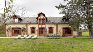 Un bâtiment à la façade en briques, doté de grandes fenêtres et d’une pelouse agrémentée de chaises longues.