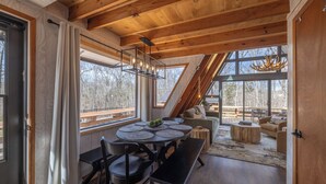 A modern interior with a wooden ceiling, large windows, a dining area with round tables, and a cozy seating area. - Chalet Harmonie by Innsbrook Vacations! (Innsbrook)