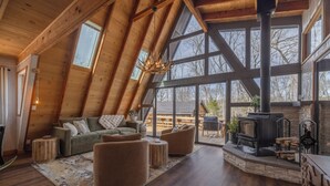 A spacious loft with a high ceiling, large windows, a fireplace, and a cozy seating area. - Chalet Harmonie by Innsbrook Vacations! (Innsbrook)