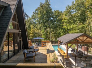 Une terrasse en bois avec des meubles d’extérieur, une piscine et un espace abrité avec des sièges.