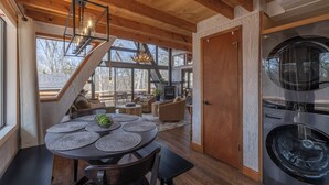 A modern interior with a dining area, staircase, and a large washer-dryer unit. - Chalet Harmonie by Innsbrook Vacations! (Innsbrook)
