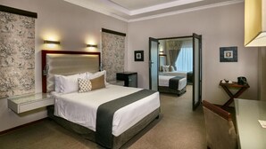A hotel room with a large bed, bedside tables, a mirror, and a desk with a chair. - Golden Crystal Hotel (Gaborone)
