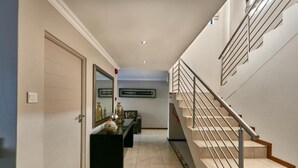 A modern interior with a staircase, a hallway, and a door leading to another room. - Golden Crystal Hotel (Gaborone)