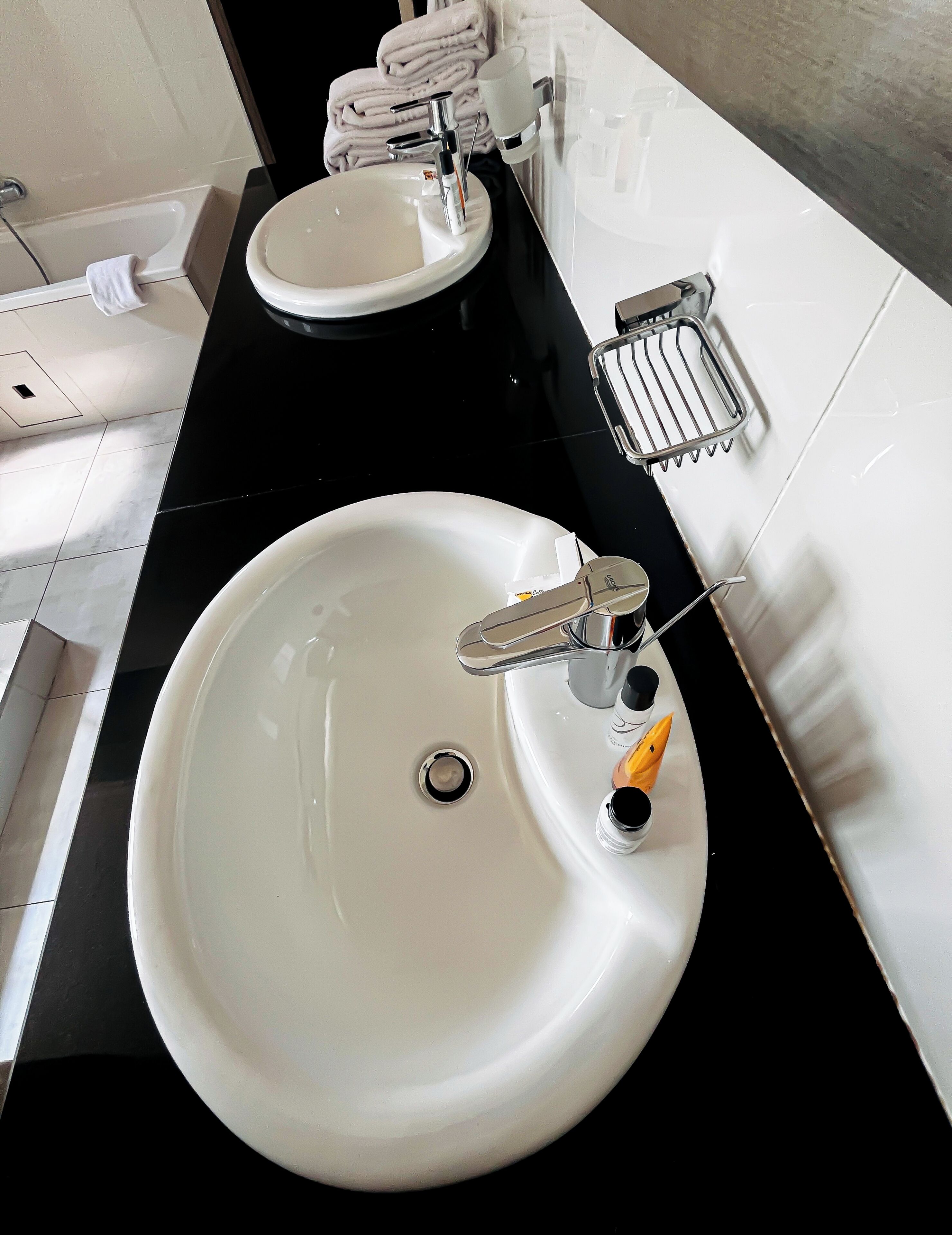 A bathroom with a white sink, a mirror, and a towel rack with folded towels.