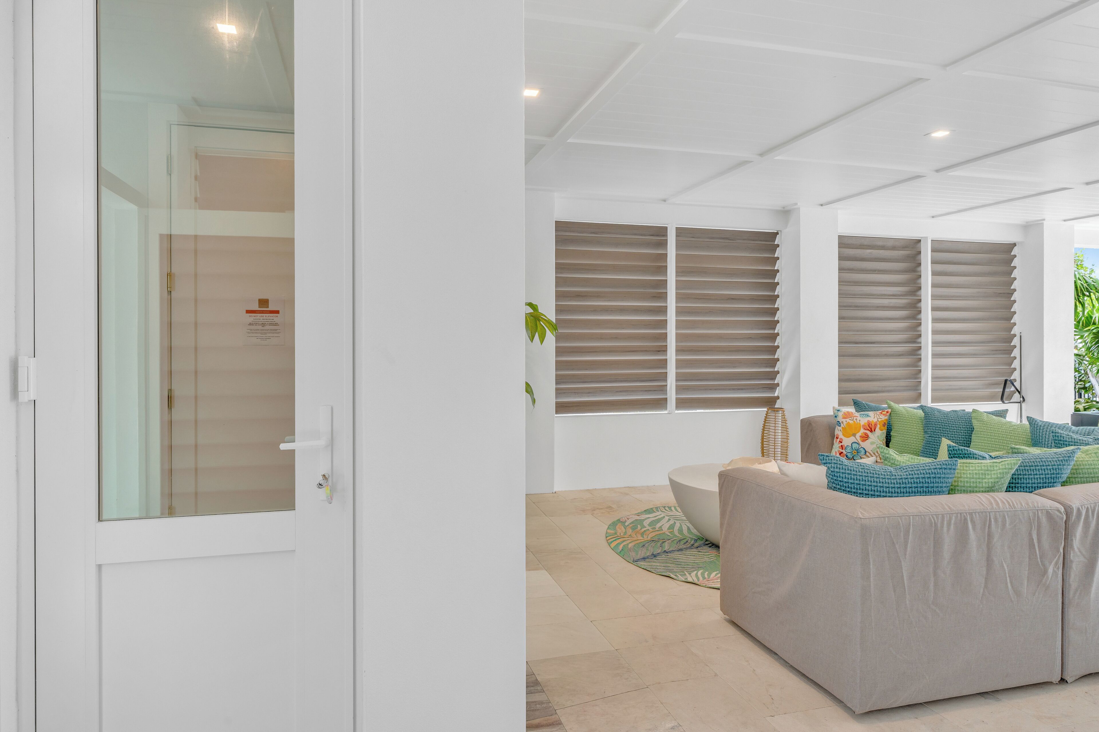 Un soggiorno moderno con un divano color beige, una porta in vetro e vista su un balcone.