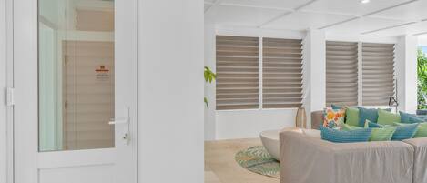 Un soggiorno moderno con un divano color beige, una porta in vetro e vista su un balcone.