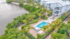 Un resort con varias edificaciones blancas, una piscina y vegetación circundante.