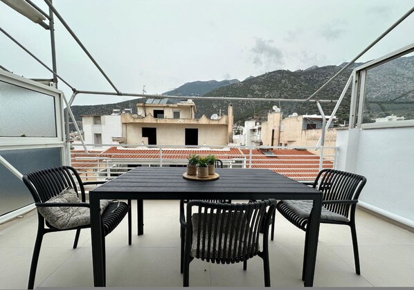 A balcony with a table and chairs, overlooking a mountainous landscape. - Loutraki s Hideaway in Loutraki (Loutraki-Agioi Theodoroi)