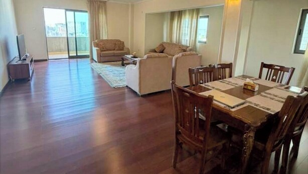 A spacious living area with a dining table, chairs, a sofa, and a balcony with a sliding door. - Luxury Oasis: 2-bedroom apartment w/ downtown city views (Addis Ababa)