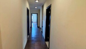 A narrow, well-lit hallway with a tiled floor, leading to a door at the end. - Luxury Oasis: 2-bedroom apartment w/ downtown city views (Addis Ababa)