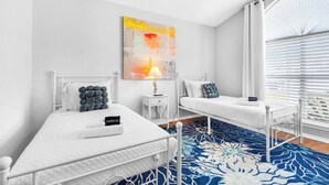 A bedroom with two beds, a ceiling fan, a large abstract painting, and a view of the outdoors through the window. - Family Friendly Pensacola Home Near Gulf Breeze (Pensacola)