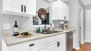 A kitchen with white cabinets, a stainless steel sink, and a wine bottle. - Family Friendly Pensacola Home Near Gulf Breeze (Pensacola)