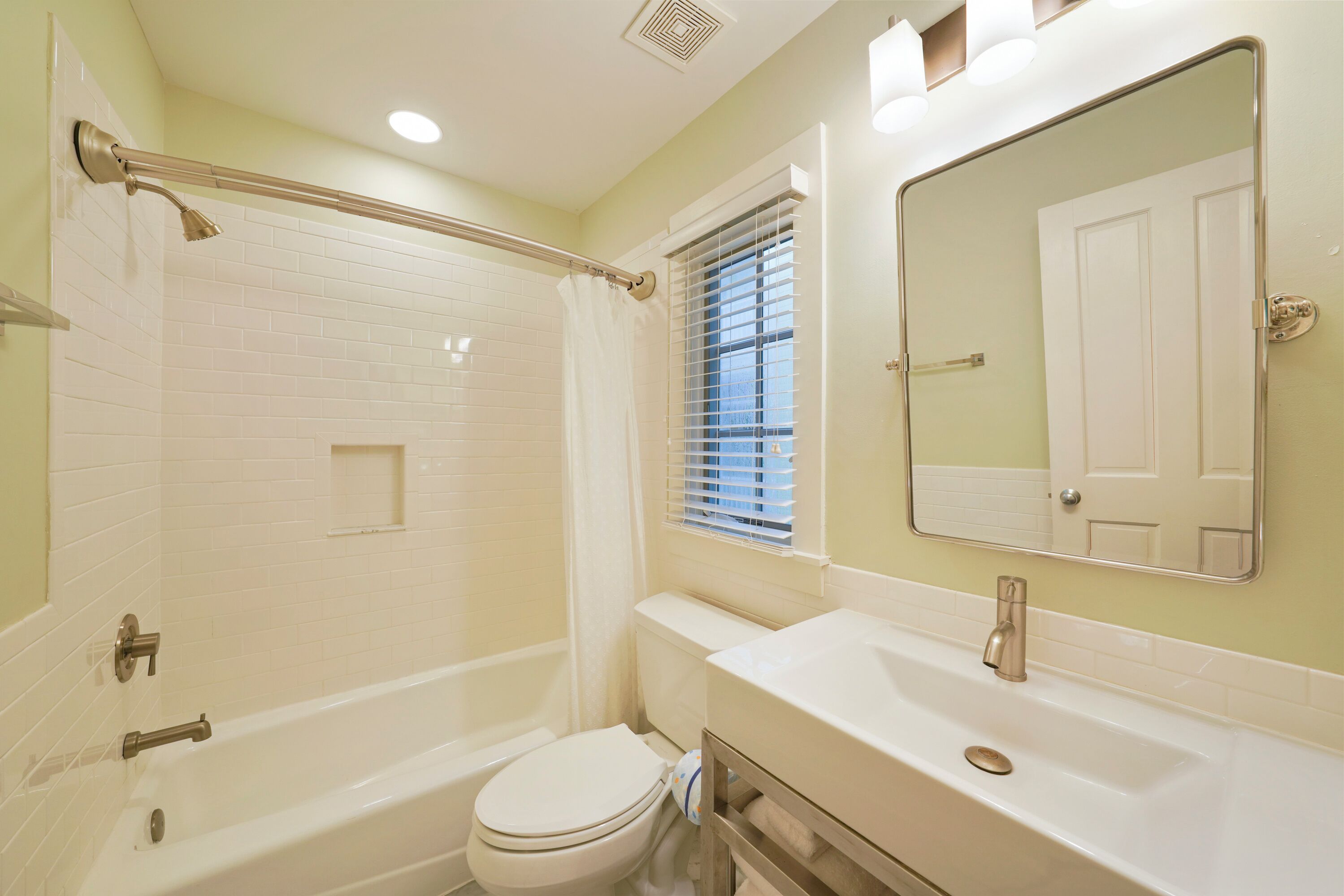 A bathroom with a bathtub, toilet, sink, and a mirror.