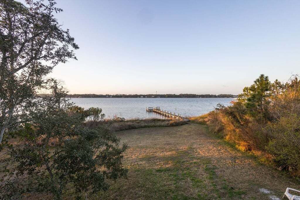 Paisaje costero con un muelle que se adentra en aguas tranquilas, rodeado de vegetación natural.