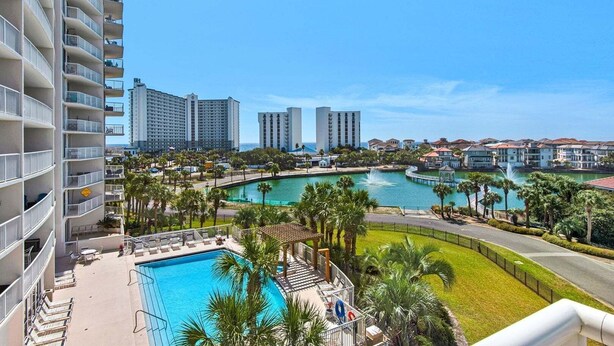 A hotel with a pool, palm trees, and a view of other buildings. - Terrace At Pelican Beach 401 3 Bedroom Home (Destin)