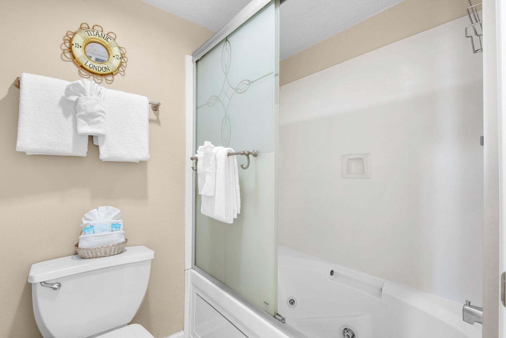 A bathroom with a toilet, a shower with a glass door, and a towel rack with white towels.