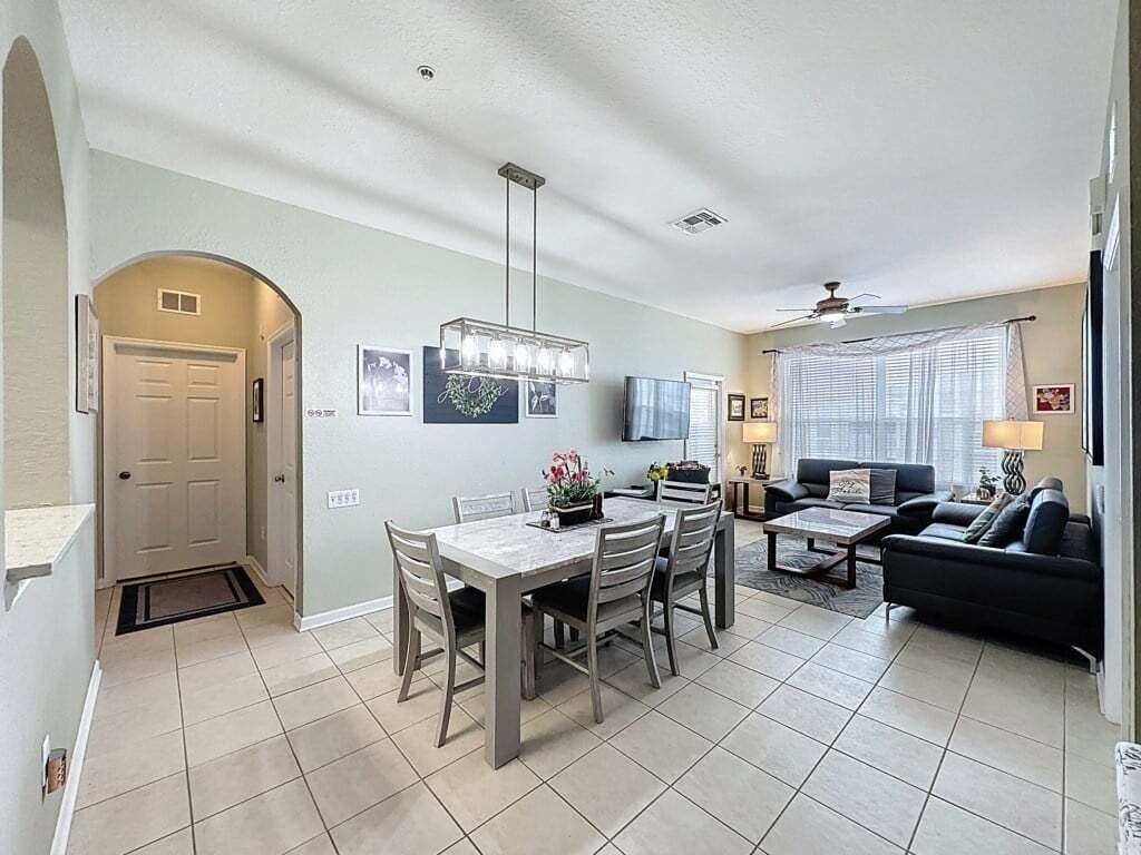 Un espacio habitable amplio con una mesa de comedor, un sofá y un ventilador de techo.