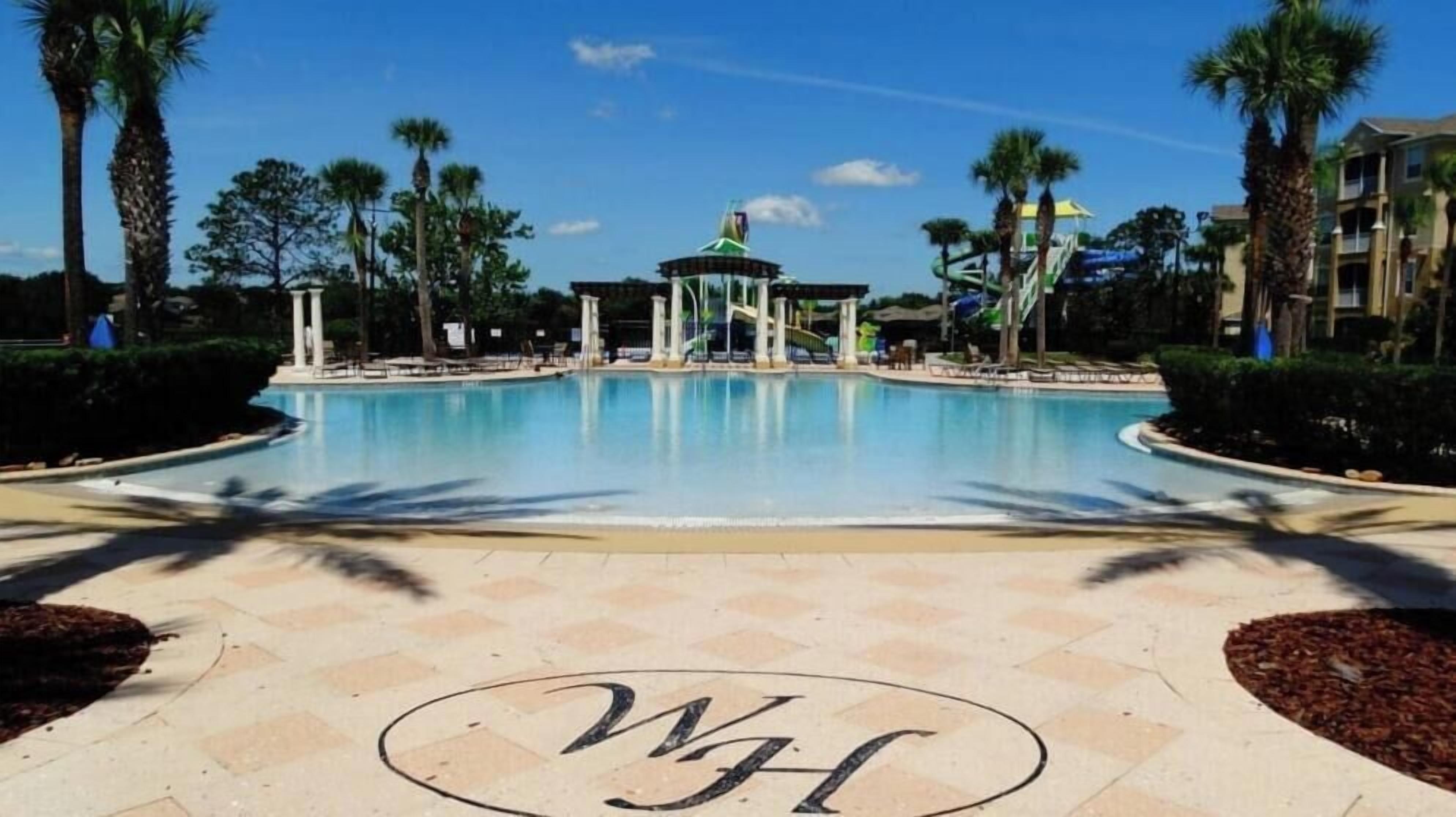A swimming pool with a gazebo in the center, surrounded by palm trees and a clear sky.