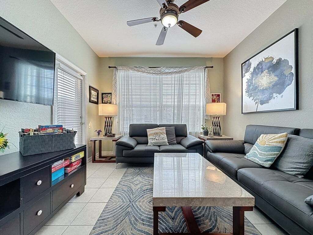 A living room with a sofa, coffee table, TV, and ceiling fan.