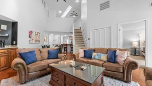 A spacious living room with two brown leather sofas, a glass coffee table, and a staircase leading to an upper level. - Pr66-8 4 Bedroom Condo (Branson)