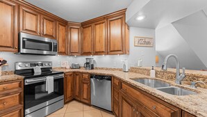A kitchen with wooden cabinets, stainless steel appliances, granite countertops, and a built-in dishwasher. - Pr66-8 4 Bedroom Condo (Branson)