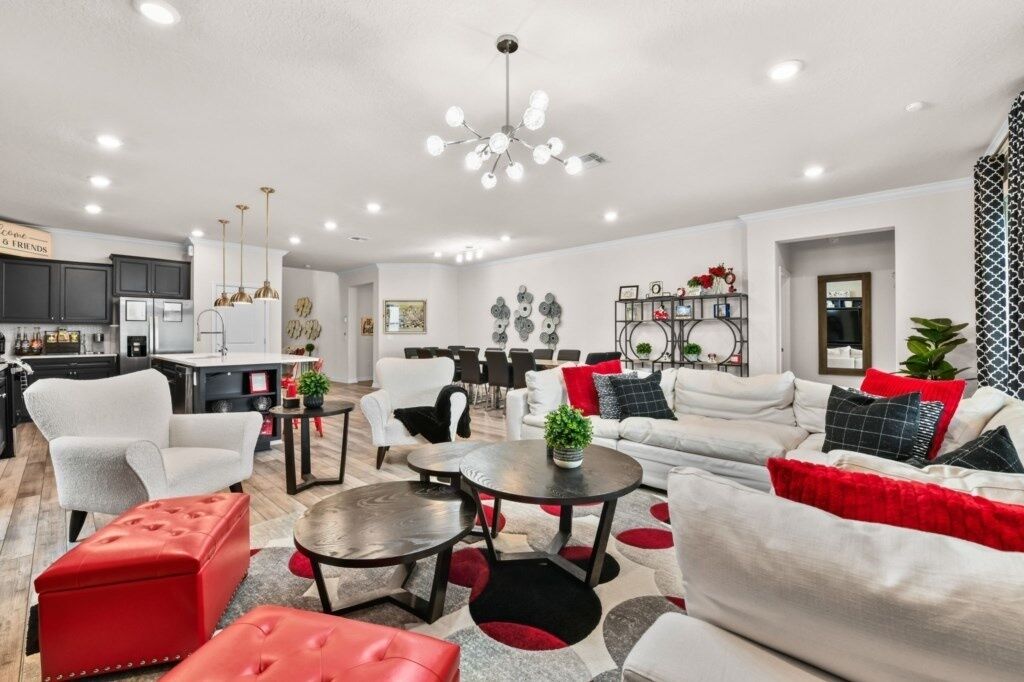 A modern living room with a sofa, armchairs, and a dining area with a table and chairs.