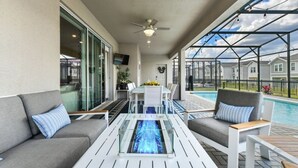Ett takförsett utomhusområde med en pool, sittplatser och en takfläkt.