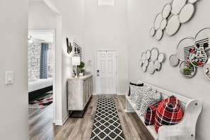 A hallway with a wooden floor, a white door, a bench with plaid cushions, and wall-mounted mirrors. - New Listing! Windsor Island-2166 8br · Disney 8 Bedroom Home (Davenport)