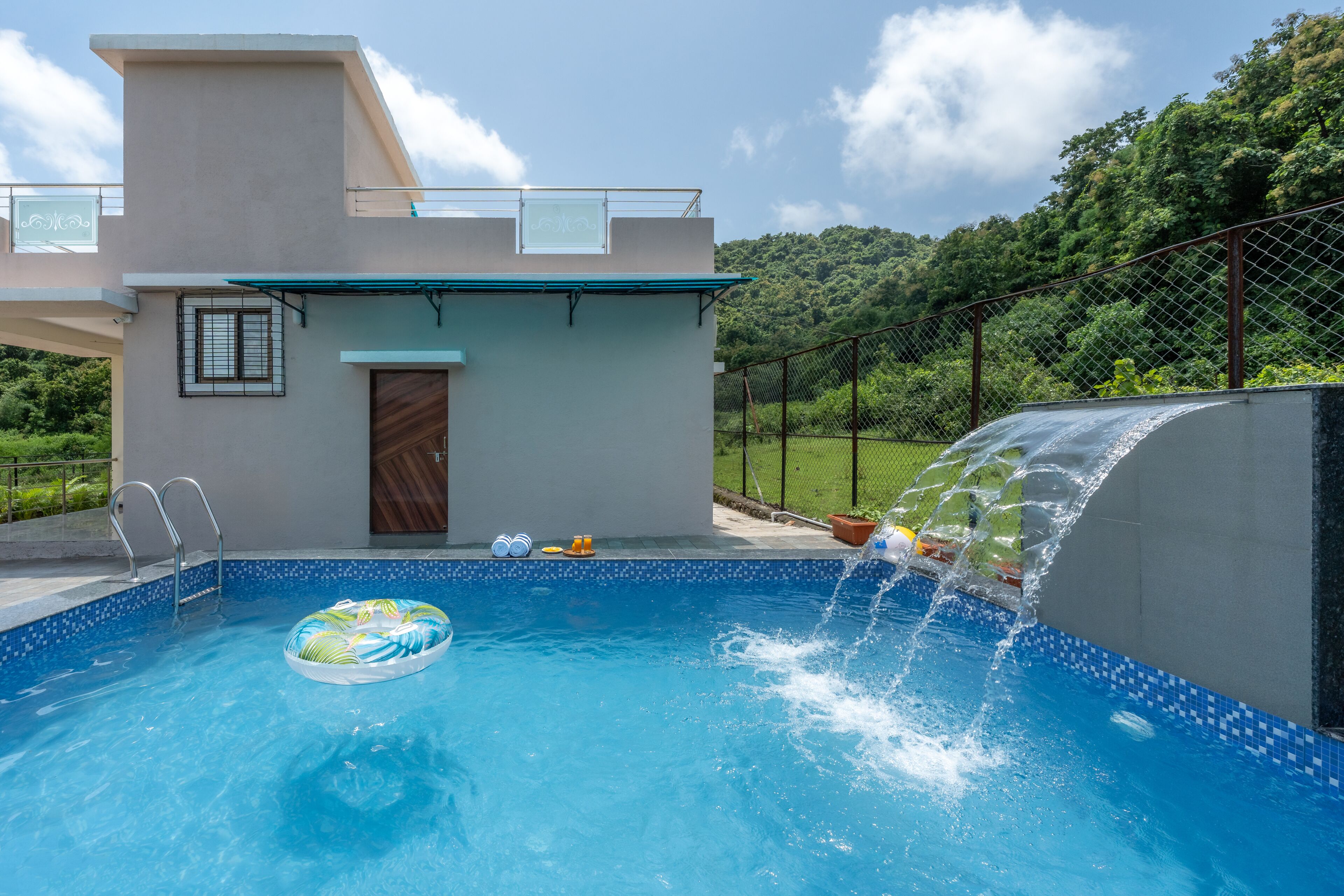 A swimming pool with a water feature, a ladder, and a door.