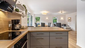 Een moderne keuken met een houten aanrechtblad, inbouwapparatuur en een eethoek met een tafel en stoelen.