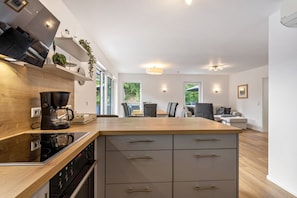 Una cocina moderna con encimera de madera, electrodomésticos integrados y un comedor con mesa y sillas.