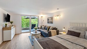 Un dormitorio con cama, sofá, televisión, escritorio y ventana.