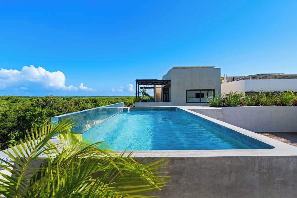 A modern pool area with a clear view of the sky and surrounding greenery.