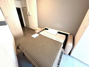 A hotel room with a bed, a bedside table, and a door leading to a bathroom. - Apartment sleeps 2 Corte center (Corte)