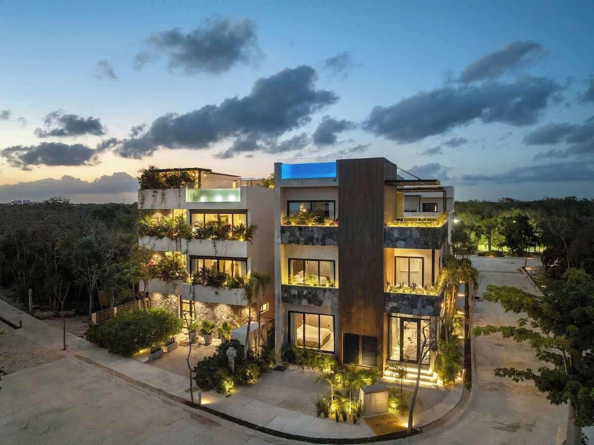 A multi-story hotel with balconies, outdoor lighting, and a view of the surrounding landscape.