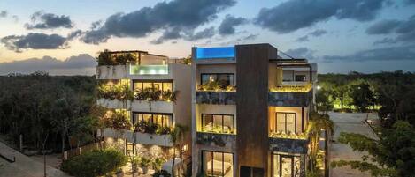 A multi-story hotel with balconies, outdoor lighting, and a view of the surrounding landscape.