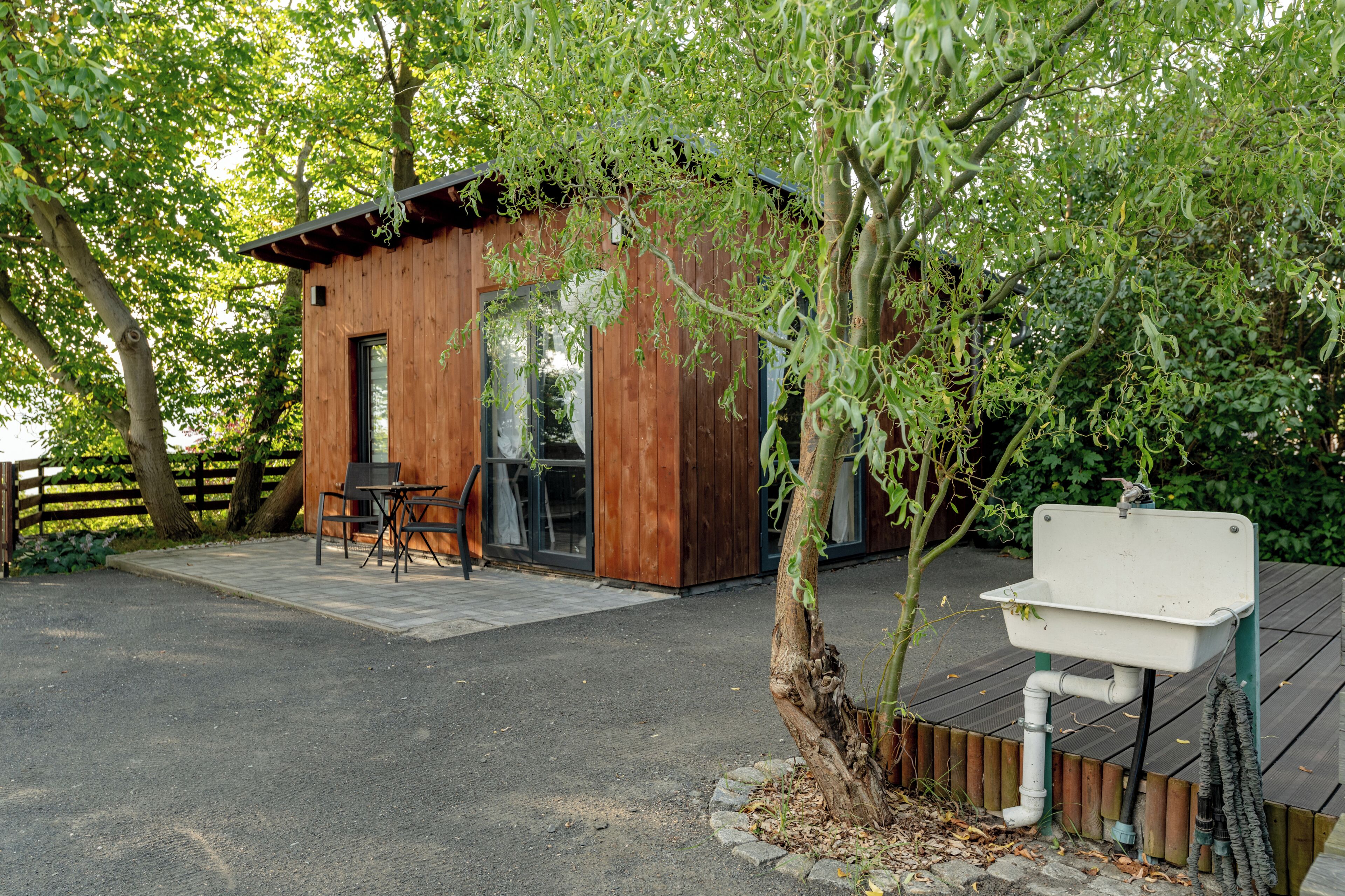 A wooden cabin with a patio area, a sink, and a table with chairs.