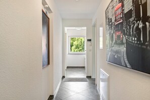 A hallway with a view of a window, a door, and a wall-mounted picture.