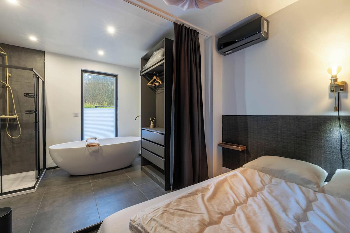 A modern bathroom with a freestanding bathtub, a walk-in shower, and a large window.