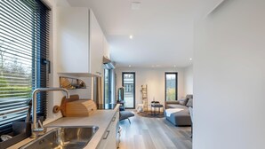 A modern kitchen with a stainless steel sink, wooden cutting board, and a built-in oven. - Vakantiepark In Style (Menaldum)