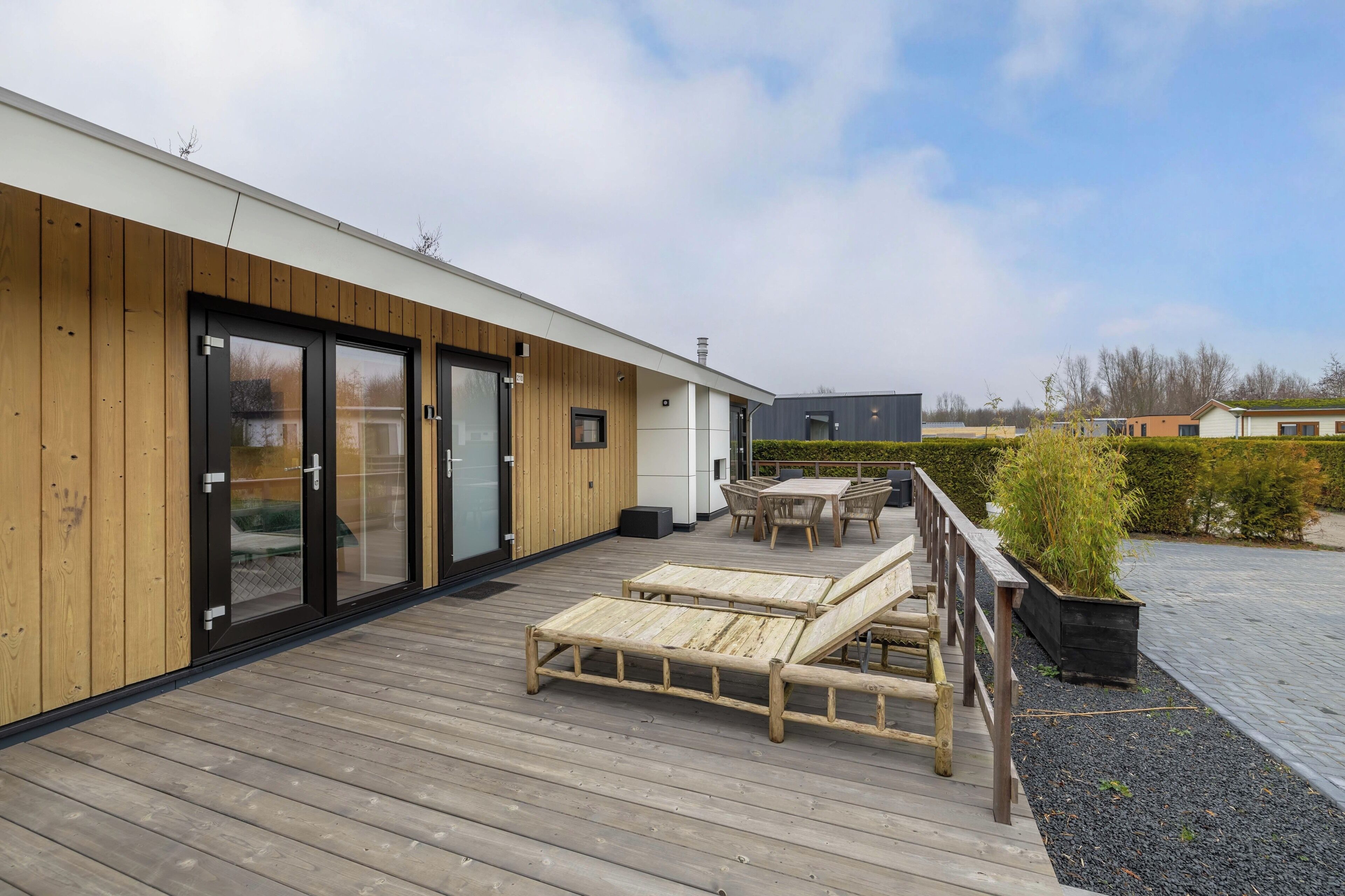 A modern building with a wooden deck, outdoor seating, and a view of the surrounding area.
