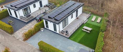 A modern two-story house with solar panels, a deck, and a well-maintained lawn.
