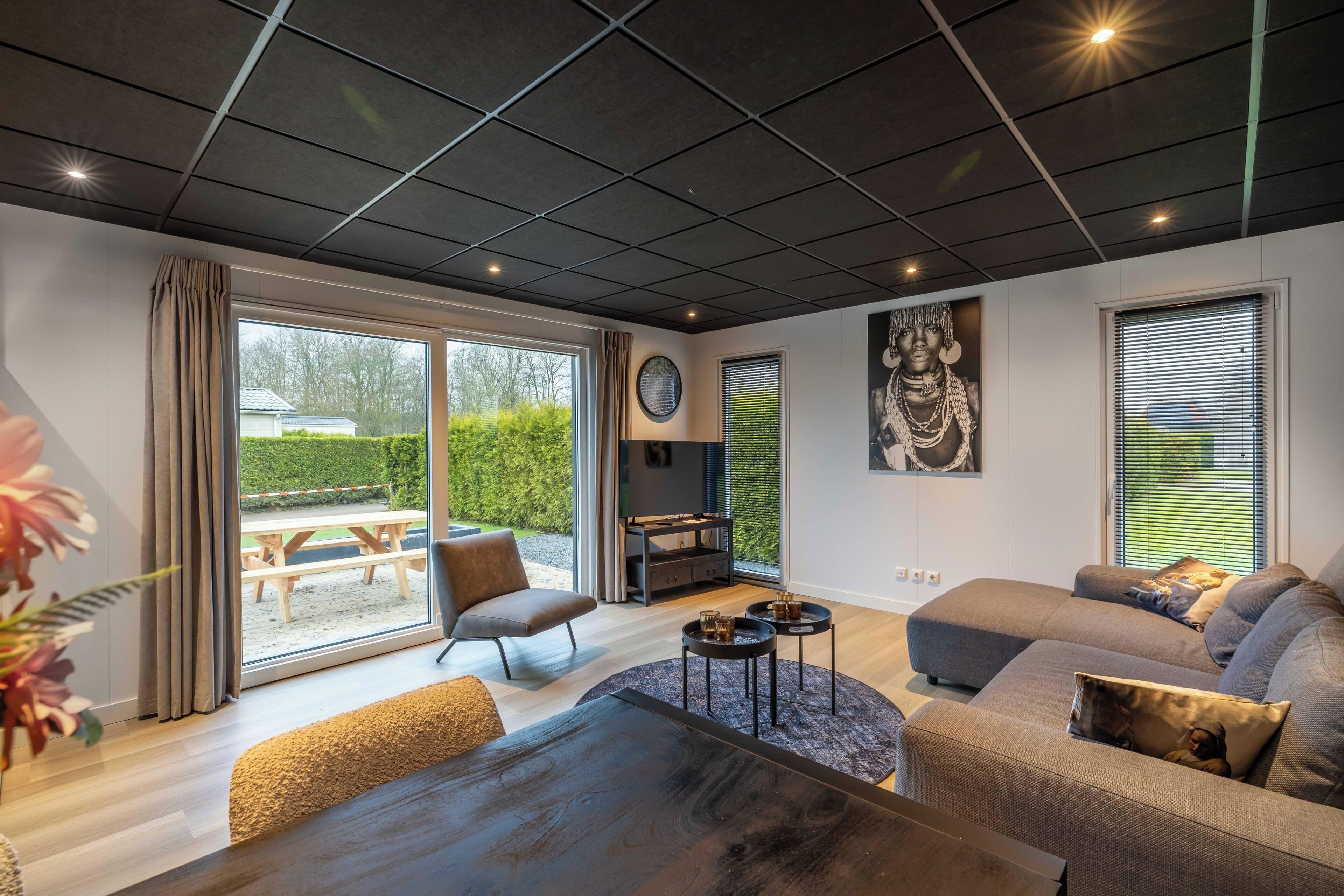 Una sala moderna con un sofá, una mesa de centro, un televisor y un amplio ventanal con vistas al exterior.