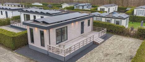A modern house with solar panels, a covered porch, and a paved driveway.